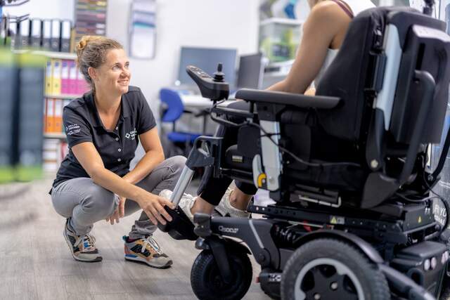 Photo d'une orthopédiste et d'un patient en chaise roulante